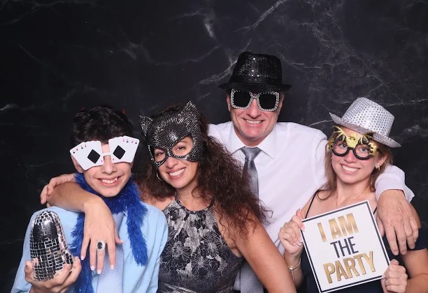 Family dressed up with props at marble backdrop photo booth
