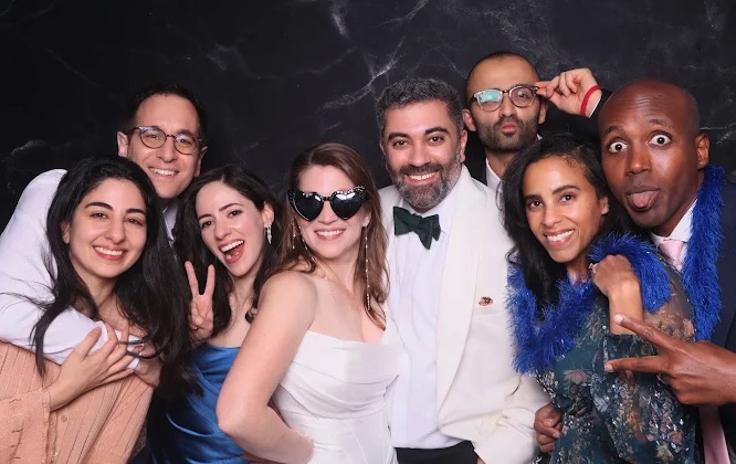 Wedding guests having fun at marble backdrop photo booth